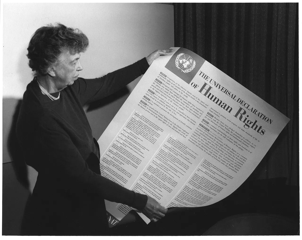 Eleanor Roosevelt, presidenta de la Comisión de Derechos Humanos de la ONU, sostiene una copia en inglés de la Declaración Universal de los Derechos Humanos, poco después de su adopción el 10 de diciembre de 1948. Esta histórica fotografía simboliza el compromiso global con la dignidad, la libertad y la igualdad para todos los seres humanos.